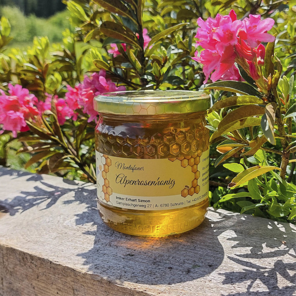Glas Alpenrosenhonig vor einem Strauch Alpenrosen