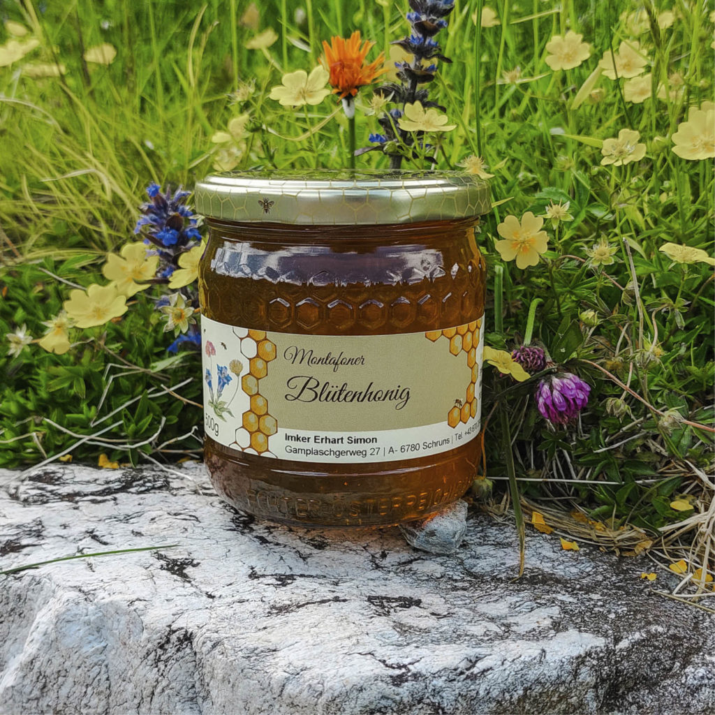 Glas Blütenhonig vor einer Blumenwiese
