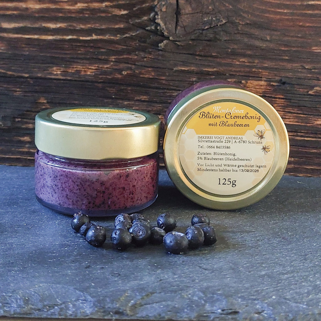 Glas Blütencremehonig mit Heidelbeeren auf Schieferplatte