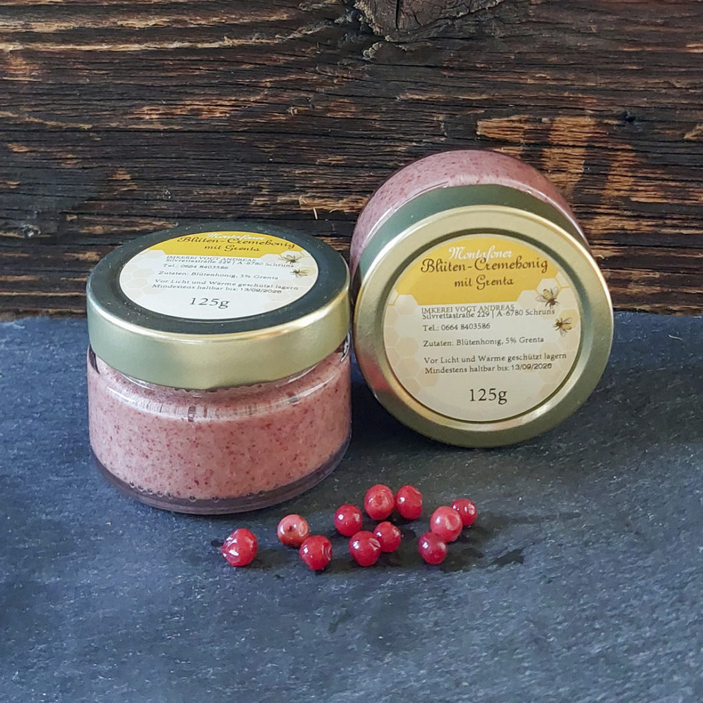 Glas Blütencremehonig mit Preiselbeeren auf Schieferplatte