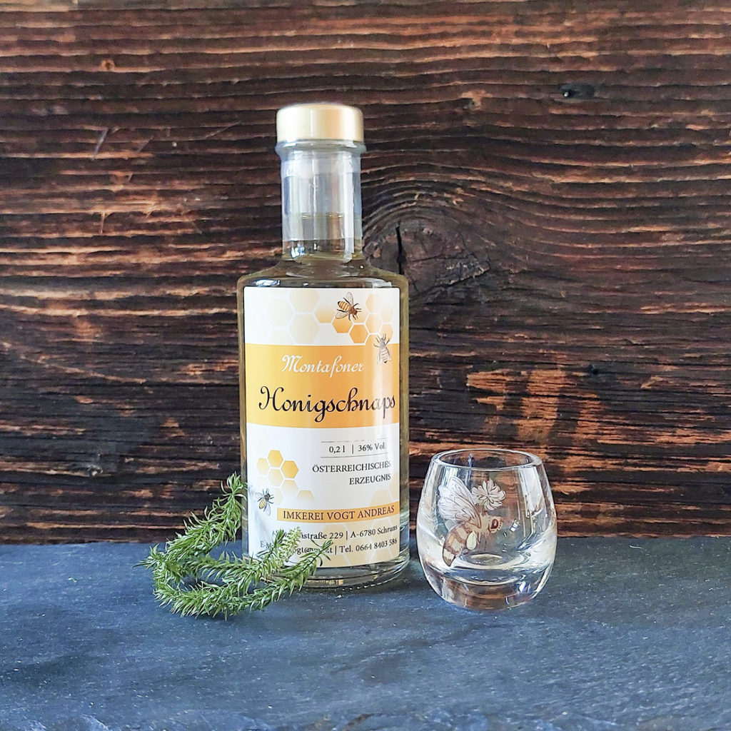 Kleine Flasche Honigschnaps mit Schnapsglas als Dekoration