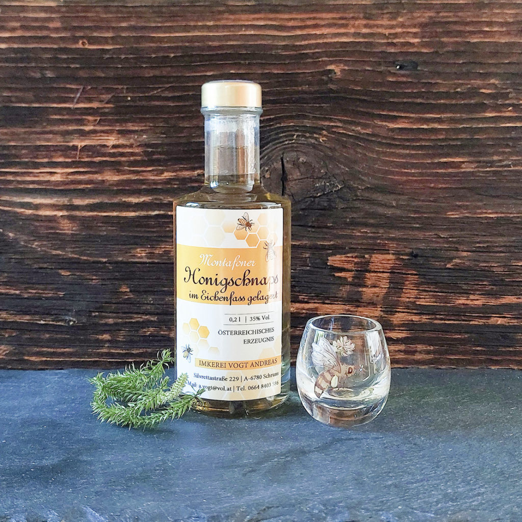 Kleine Flasche Honigschnaps aus dem Eichenfass mit Schnapsglas als Dekoration