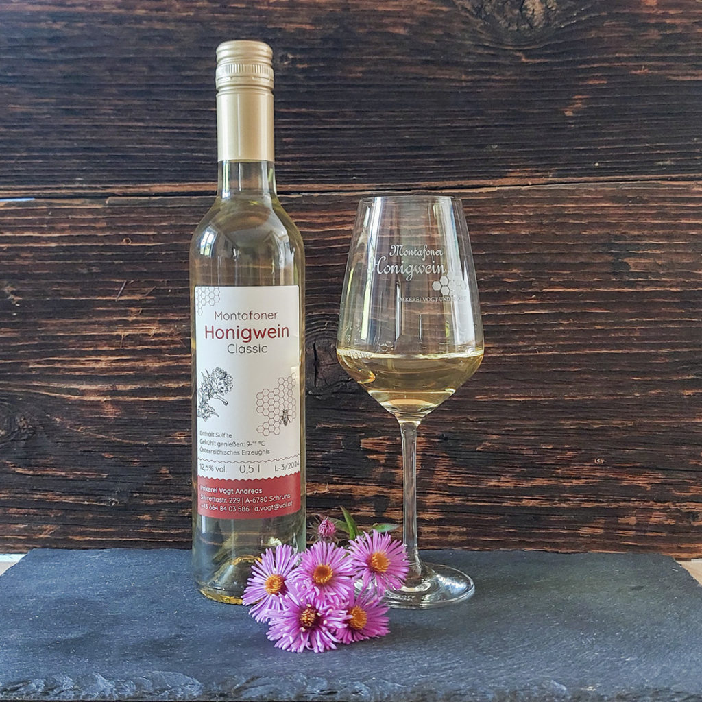 Flasche Honigwein auf Schiefertafel mit Weinglas zur Dekoration und Blumen