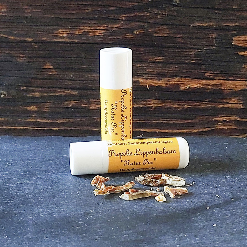 Lippenbalsam auf Schieferplatte mit Propolis im Vordergrund