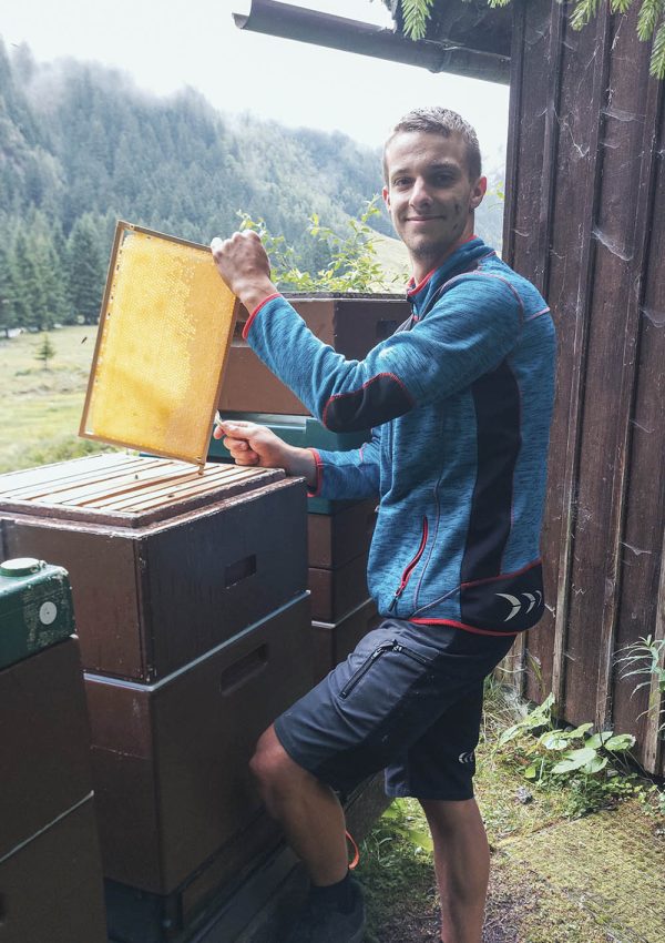 Imker Simon an Bienenstöcken mit Honigrahmen